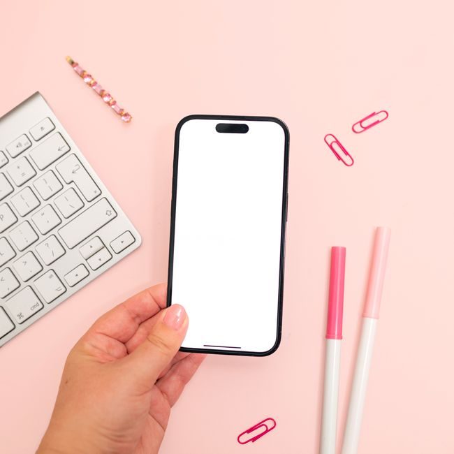 A minimalistic pink-themed workspace showcasing a smartphone mockup held in hand. — Jilly Noble, Pexels