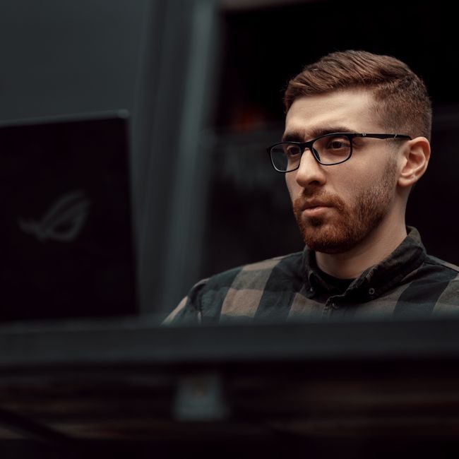 Portrait of a serious man with glasses working on a laptop indoors, showcasing concentration and focus. — Mohammad Hossein Mirzagol, Pexels