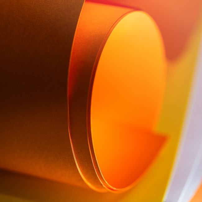 A vibrant and abstract close-up of an orange paper roll with warm lighting. — Jakub Zerdzicki, Pexels