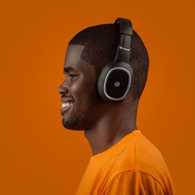 Profile of a smiling man wearing headphones against a vibrant orange background. — Smooth Models, Pexels