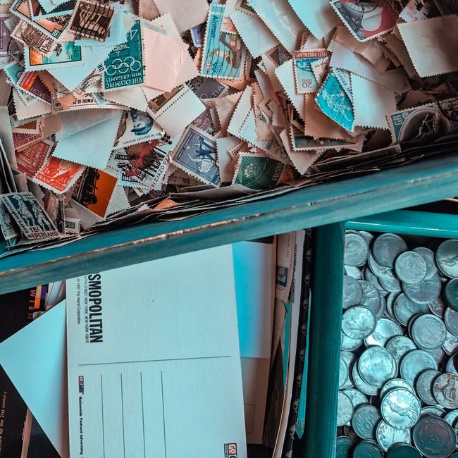 Top view of vintage stamps, postcards, and coins in a collector's box, showcasing nostalgia. — Yusuf Kocapınar, Pexels