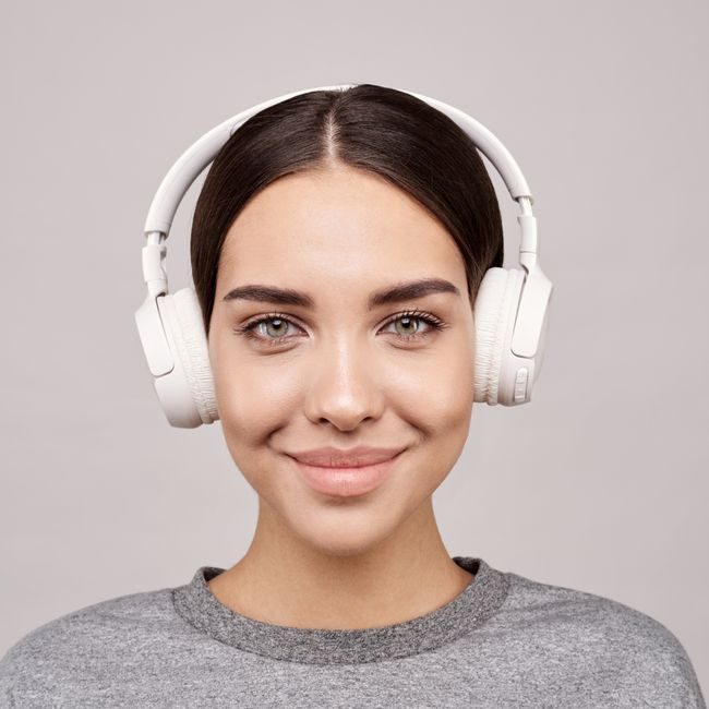 Portrait of a smiling woman wearing headphones, enjoying music indoors. — Sound On, Pexels