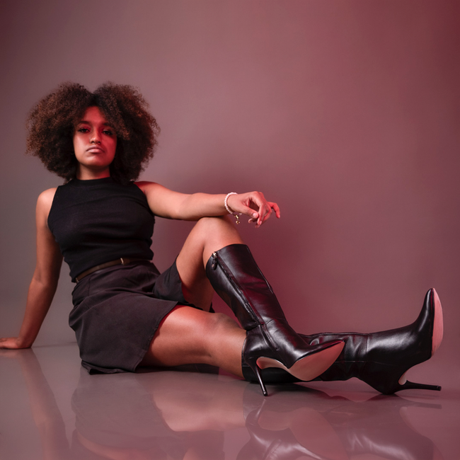 Portrait of a young woman wearing black skirt and tall leather boots in a studio setting. — José Martin Segura Benites, Pexels