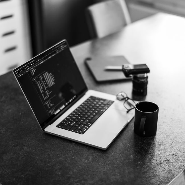 Black-and-white photo of a laptop on a table with coffee, perfect for remote work themes. — Boris K., Pexels