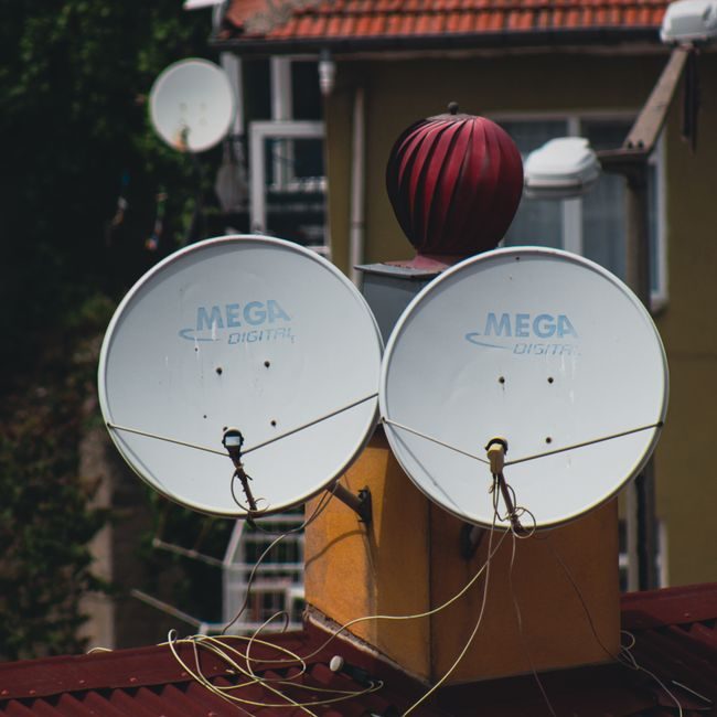 A pair of satellite dishes on a rooftop, capturing signals against an urban backdrop. — Barış Yiğit, Pexels