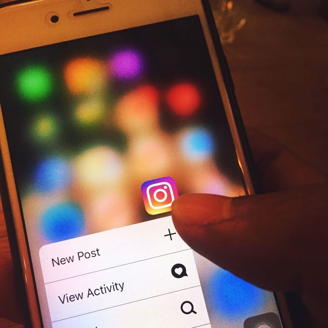 Finger navigating Instagram app on a smartphone screen with colorful blurred background. — Omkar Patyane, Pexels