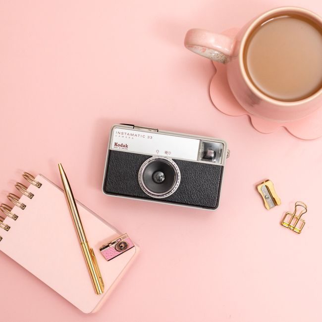 Flat lay of a vintage Kodak camera with pink stationery and coffee on a pink desk. — Jilly Noble, Pexels