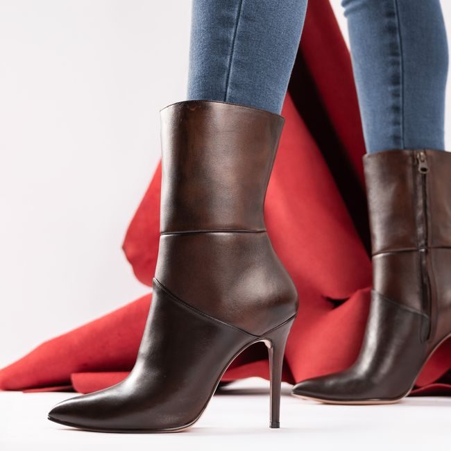 Stylish brown leather stiletto boots with elegant design, highlighted against a red fabric backdrop. — José Martin Segura Benites, Pexels