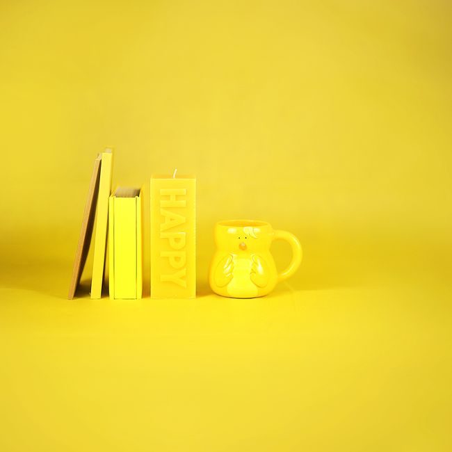 Monochrome chick shaped cup placed near candle with Happy inscription and stationery on yellow background — Karen Laårk Boshoff, Pexels