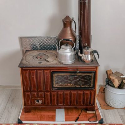 A rustic Turkish wood-burning stove with metal teapots and wood fuel, showcasing traditional cooking methods. — Zülfü Demir📸, Pexels