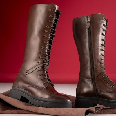 Elegant brown leather knee-high boots with lace and zipper on red background. — José Martin Segura Benites, Pexels