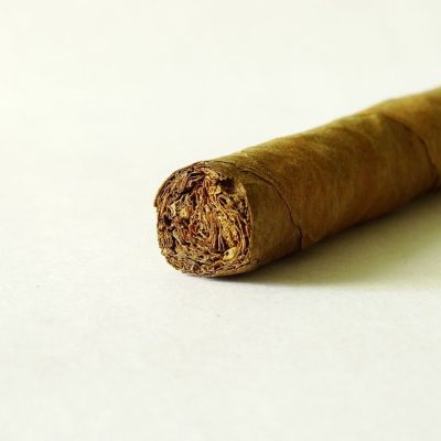 Close-up of a rolled tobacco cigar on a white background, emphasizing texture and detail. — Siva Madurai, Pexels
