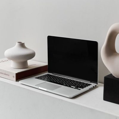 A sleek laptop on a modern desk alongside stylish ceramic vases, embodying minimalism. — Claire  Ló, Pexels