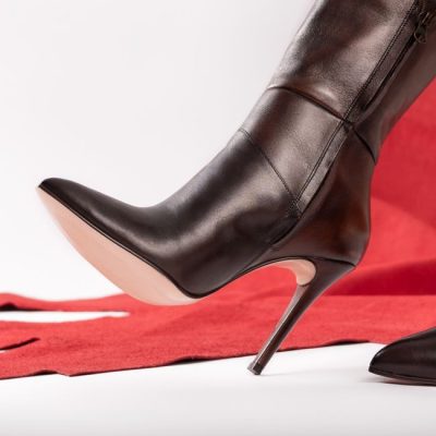 Close-up of a black leather stiletto boot on a red background, showcasing elegance and style. — José Martin Segura Benites, Pexels