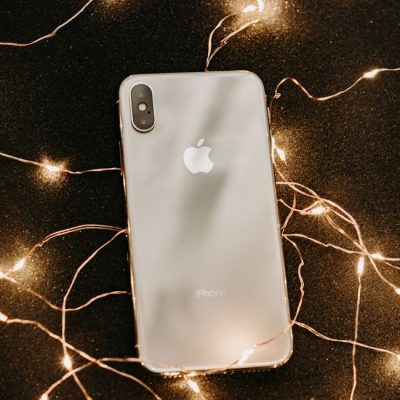 A sleek smartphone surrounded by glowing fairy lights on a dark surface for a luxurious effect. — Irina Iriser, Pexels