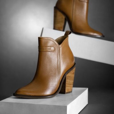Stylish brown leather ankle boots with high heels on white pedestals for fashion branding. — José Martin Segura Benites, Pexels