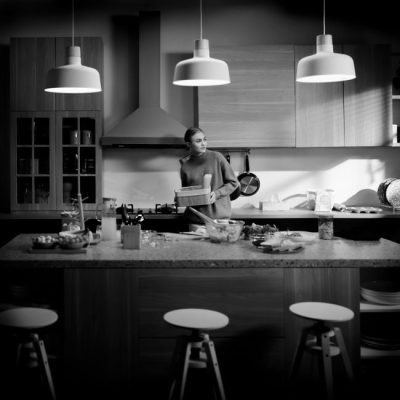 Stylish black and white kitchen interior featuring a woman preparing a meal in Jakarta. — Daniel Lee, Pexels