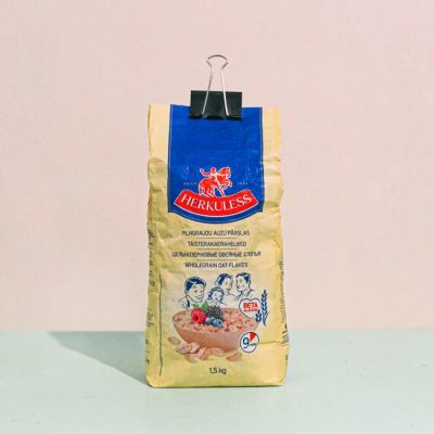 Pack of Herkuless wholegrain oat flakes secured with a binder clip on a pastel background. — Elīna Arāja, Pexels