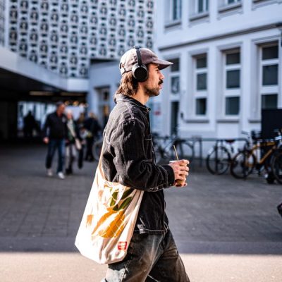 Casual street scene in Trier, Germany, featuring a man with headphones and drink. — Hakan Sapci, Pexels