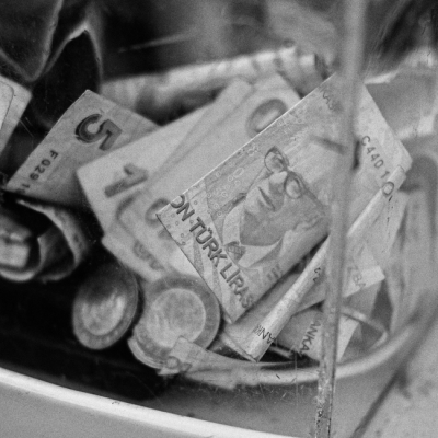 Black and white close-up of Turkish Lira notes and coins in a container. — Enes Akdoğan, Pexels