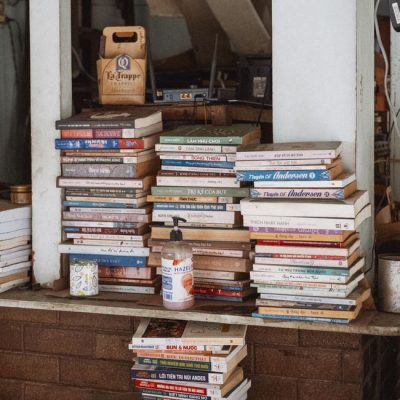 A diverse collection of stacked books in a cozy indoor setting with warm lighting. — Nguyen Duc Toan, Pexels