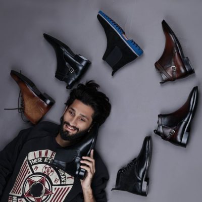 A stylish man lies against a gray background surrounded by leather shoes, showcasing fashion and elegance. — Danyal Malik, Pexels