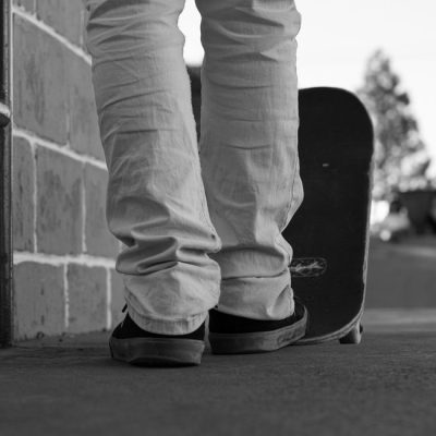 A low-angle view of a skateboarder in casual attire standing with a skateboard outdoors. — Oliver Alexandre Reinis, Pexels