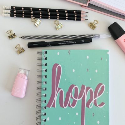 Flat lay of pink and teal desk supplies with a hope-themed notebook, inspiring productivity. — Andrea Nascimento, Pexels