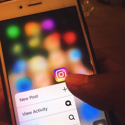 Finger navigating Instagram app on a smartphone screen with colorful blurred background. — Omkar Patyane, Pexels