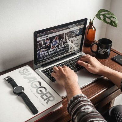 A person working on a laptop at a desk with a watch and mug, perfect for a productivity concept. — Drew Williams, Pexels
