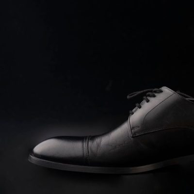 Detailed close-up of a classic black leather Oxford shoe against a dark background. — Ali Nafezarefi, Pexels