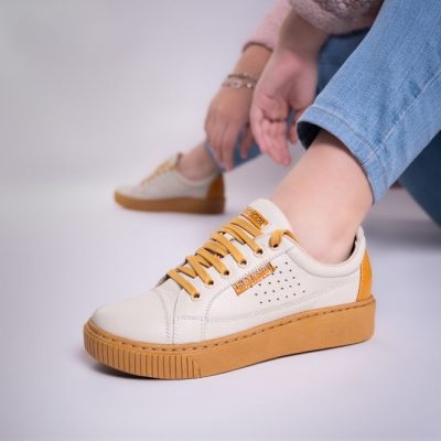 Trendy mustard sneakers styled with jeans in an indoor setting, highlighting casual footwear fashion. — José Martin Segura Benites, Pexels